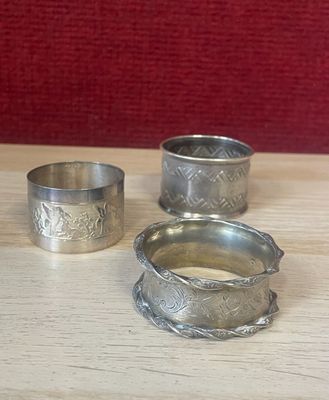 three silver rings sitting on top of a wooden table next to each other