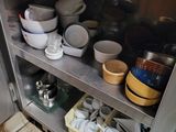 many bowls and pans on the shelves in the kitchen