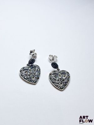 paire de boucles d'oreilles en forme de cœur en argent, ornées de cristaux bleus sur fond blanc