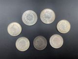 a group of five silver coins sitting on top of a black surface