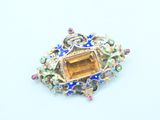 an image of a brooch with a citrine and multicolored stones