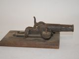 an old gun on a wooden block on a white surface
