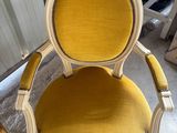une chaise jaune et blanche assise dans une pièce à côté d'un miroir