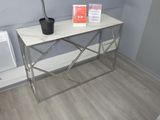 une petite table sur laquelle se trouve une plante, près d'une fenêtre