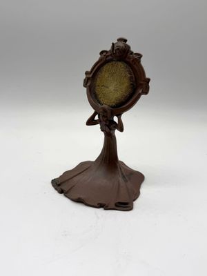 an image of a small clock on a stand on a white surface