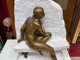 une statue de femme assise au sommet d'un rocher
