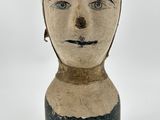 une tête d'homme en argile ornée d'une rayure noire et blanche