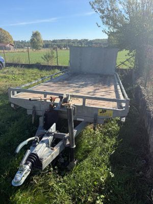 une remorque garée dans l'herbe près d'un arbre
