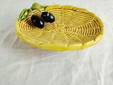 a yellow plate with two black olives on it