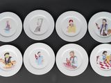 six assiettes blanches ornées de personnages de dessins animés, posées sur un fond noir