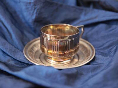 une tasse et une soucoupe en argent posées sur un napperon bleu