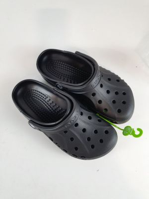 une paire de sabots noirs percés de trous, posés sur une surface blanche