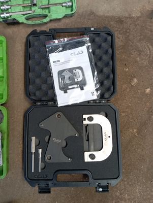 une mallette verte contenant des outils, posée par terre