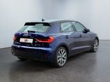 the rear end of a blue car parked in a white room