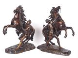 deux statues de chevaux en bronze posées sur un rocher, sur fond blanc