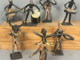 cinq figurines représentant des danseurs africains, posées sur un socle en bois