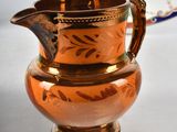 a brown pitcher sitting on a table next to a plate