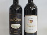 two bottles of red wine sitting next to each other on a table