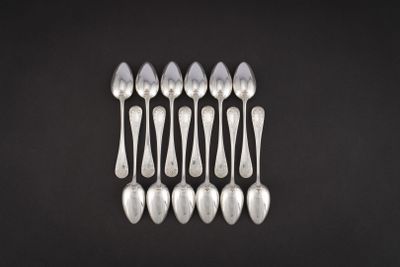 six cuillères en argent sont disposées en rangée sur une surface noire