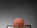 une figurine rouge et verte représentant un homme muni d'une tronçonneuse