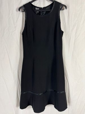 une robe noire suspendue à un cintre sur un drap blanc
