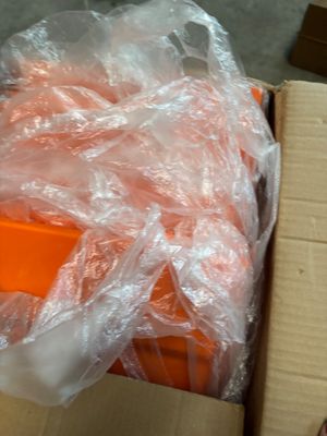 a box of oranges wrapped in plastic sitting on the floor