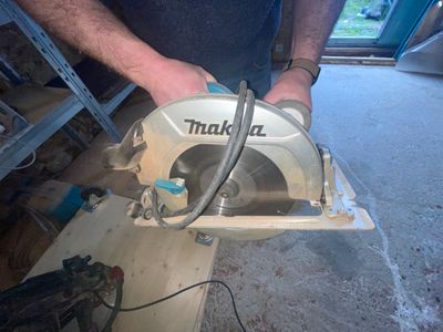 a man using a circular saw to cut a hole in a wall
