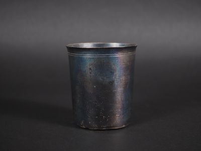 un gros plan d'une tasse en métal posée sur une surface noire