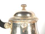 a silver tea pot with a black handle on a table