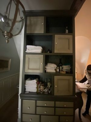 une femme debout dans une salle de bains, avec une serviette posée sur une étagère