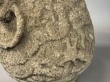 a stone sculpture of a face on a white surface
