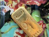 un lingot d'or posé sur une assiette, avec des fleurs en arrière-plan