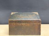 an old wooden box sitting on top of a table next to a black wall