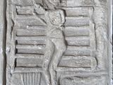 un relief en pierre représentant un homme assis sur un banc