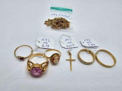 several gold rings and a cross are sitting on a table