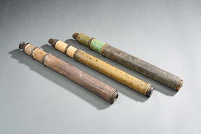 trois vieux tuyaux en bois sont alignés les uns à côté des autres sur une surface grise
