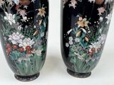 two black vases with flowers and birds painted on them