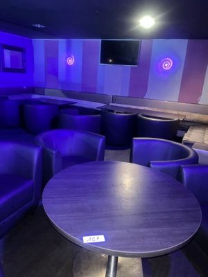 des canapés et des tables violets dans une pièce faiblement éclairée par des lumières bleues