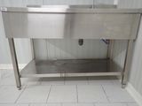 a stainless steel sink in the corner of a bathroom