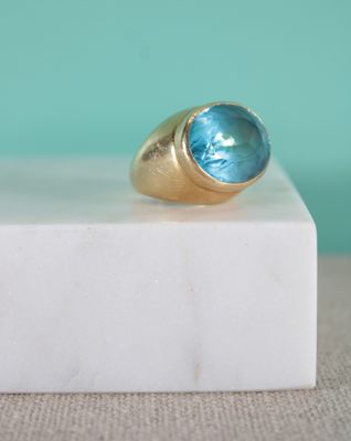 Gros plan sur une bague en or ornée d'une topaze bleue