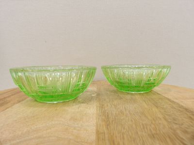 two green glass bowls sitting on top of a wooden table