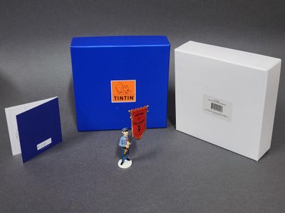 une petite figurine qui se trouve à côté d'une boîte bleue