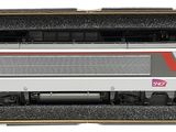 un train miniature dans une boîte ornée d'une bande rouge