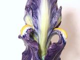 un vase orné d'une fleur violette posé sur une table blanche