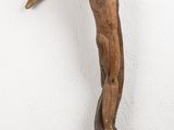 statue d'une femme posée sur un socle en bois, devant un mur blanc