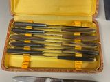 several knives in a case sitting on a table next to a knife sharper