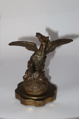 bronze statue of a bird on a pedestal with a clock in the background
