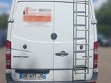 a white van parked in a parking lot with a ladder on the back of the van