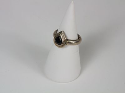 silver ring with a black stone in the middle on a white cone