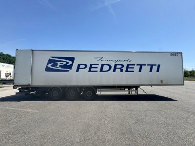 une semi-remorque blanche garée sur un parking, arborant sur le côté le logo Pedretti bleu et blanc